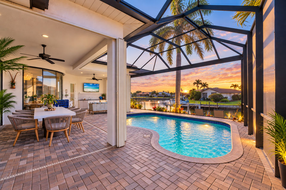 Gorgeous outdoor living space overlooking the sparkling private pool and canal beyond. Great for entertaining. This space features an outdoor kitchen, ample seating, grill, dining table that seats 8, and 50-inch Smart TV