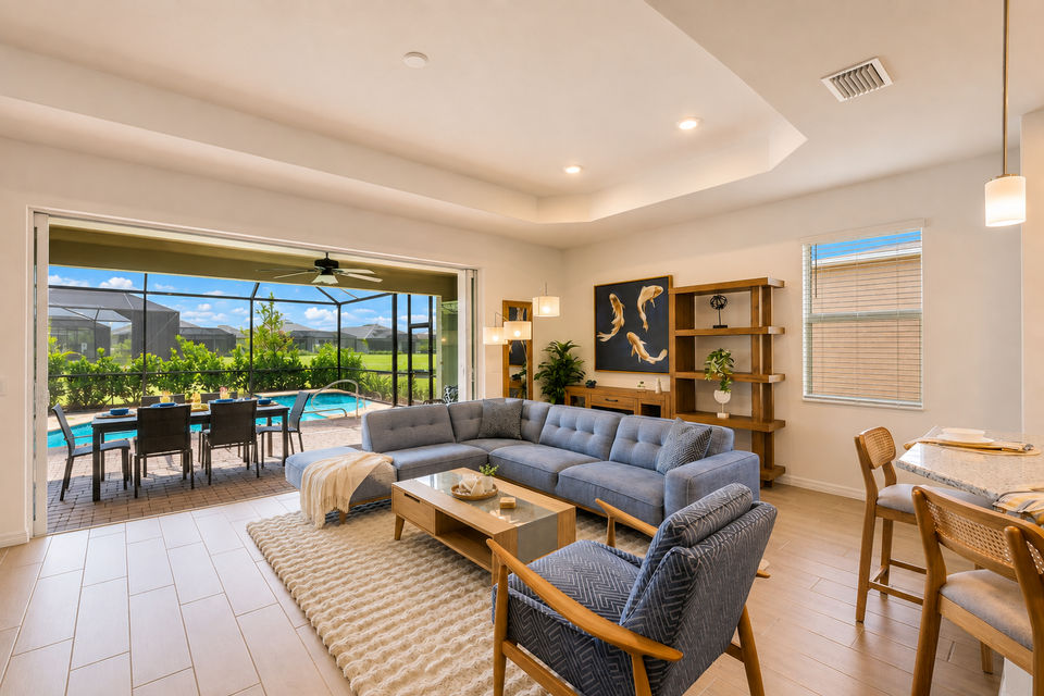 Living room overlooking the sparkling pool. Features ample seating and 85-inch Smart TV
