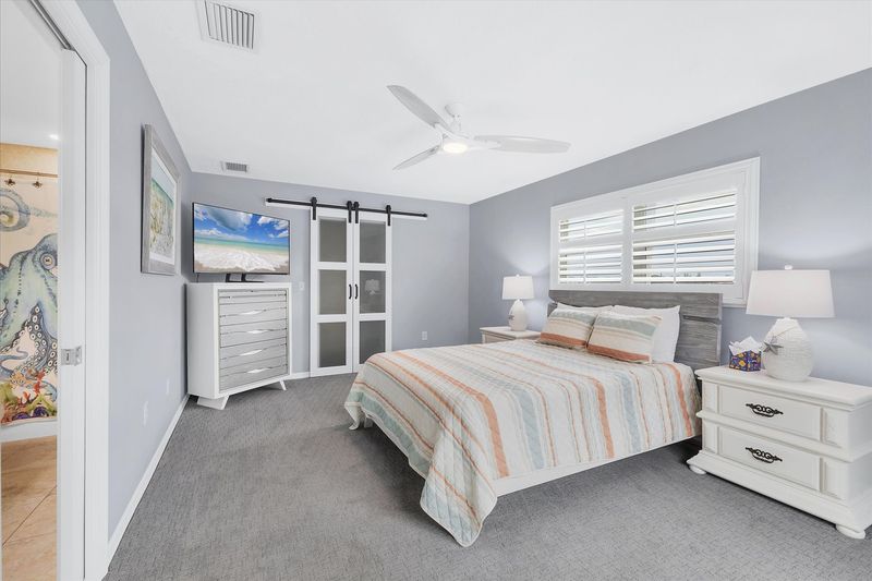 Guest bedroom with queen bed, attached bathroom, lanai access, and 50-inch Smart TV