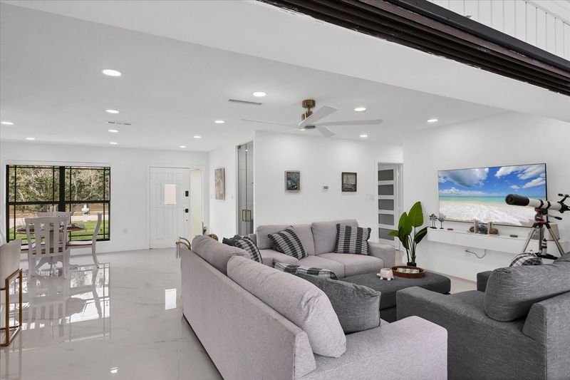 Living room overlooking the pool & canal. Living features ample & comfy seating, and 65-inch Smart TV