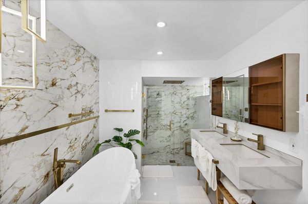 Double suite attached bathroom with walk-in shower, soaking tub, and double vanities