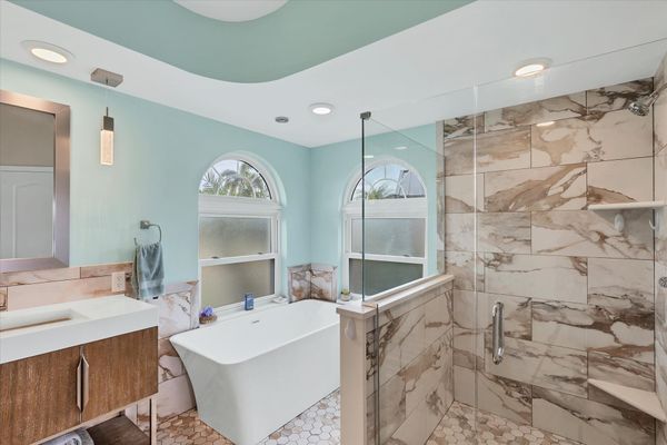 Primary attached bathroom with large walk-in shower, soaking tub, and double vanities