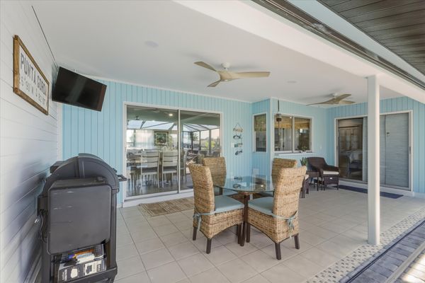 Large outdoor living space with dining table that seats 4, sun loungers, BBQ grill, sparkling pool, and 40-inch Smart TV