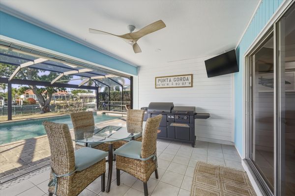 Large outdoor living space with dining table that seats 4, sun loungers, BBQ grill, sparkling pool, and 40-inch Smart TV