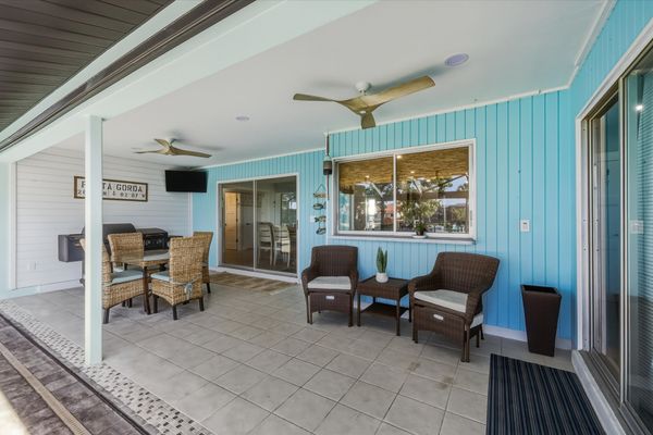 Large outdoor living space with dining table that seats 4, sun loungers, BBQ grill, sparkling pool, and 40-inch Smart TV