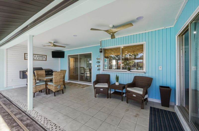 Large outdoor living space with dining table that seats 4, sun loungers, BBQ grill, sparkling pool, and 40-inch Smart TV