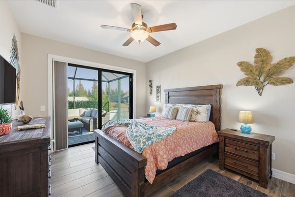 Guest bedroom 1 with queen bed, lanai access, and 40-inch Smart TV