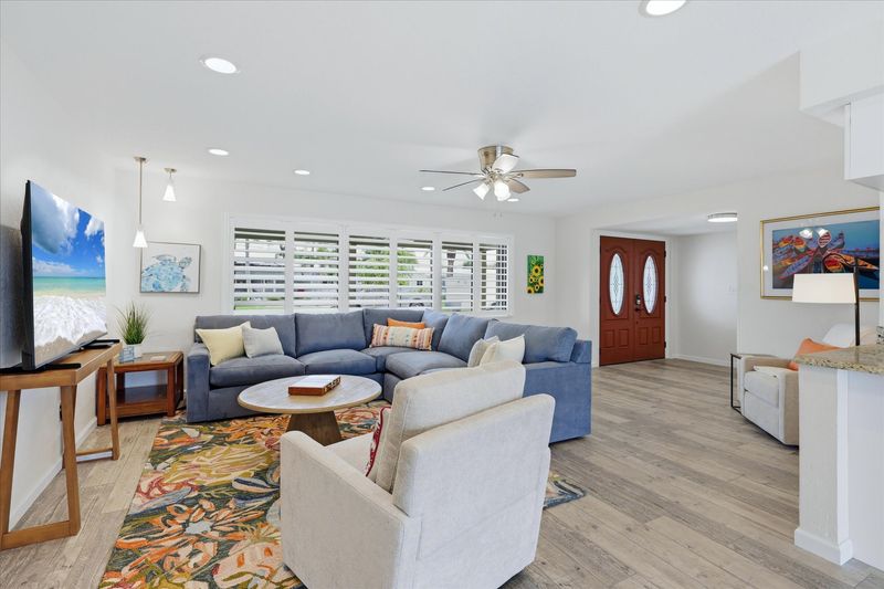 Living room overlooking the pool. Living room features lots of comfy seating, a ready nook, and 85-inch Smart TV
