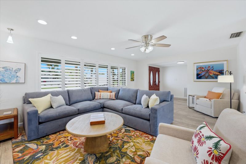 Living room overlooking the pool. Living room features lots of comfy seating, a ready nook, and 85-inch Smart TV