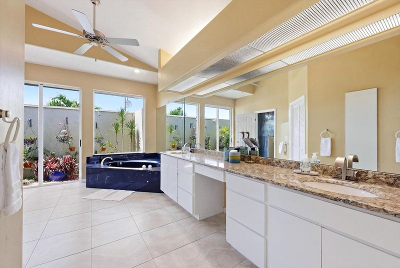 Primary bedroom's attached bathroom with walk-in shower, garden tub, double vanities, and private garden view