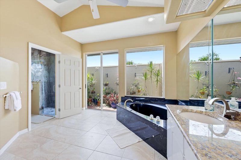 Primary bedroom's attached bathroom with walk-in shower, garden tub, double vanities, and private garden view