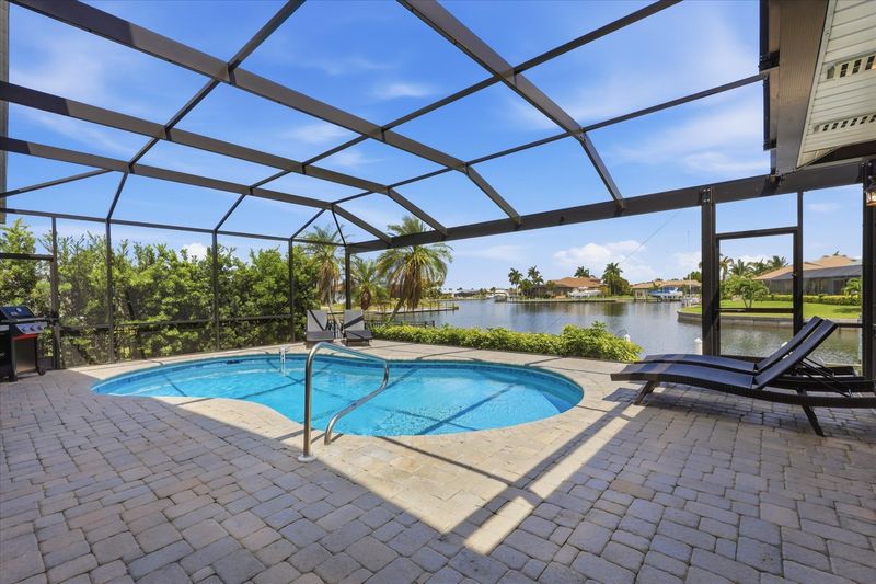 Great outdoor living space overlooking the canal. Features a sparkling pool, sun loungers, and BBQ grill. Pool size: 25' x 13' x 6'D