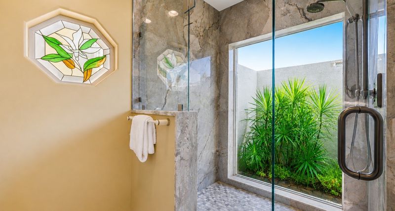 Primary bedroom's attached bathroom with walk-in shower, garden tub, double vanities, and private garden view