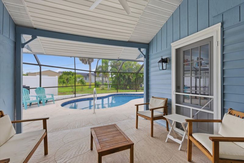 Outdoor living space overlooking sparkling pool. Also features outdoor shower, 2 sun loungers, 55-inch Smart TV, and a propane/pellet BBQ grill. Pool Size 25' x 12' x 5.5'D