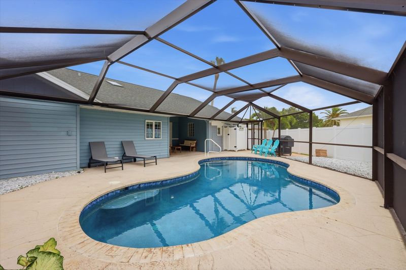 Outdoor living space overlooking sparkling pool. Also features outdoor shower, 2 sun loungers, 55-inch Smart TV, and a propane/pellet BBQ grill. Pool Size 25' x 12' x 5.5'D