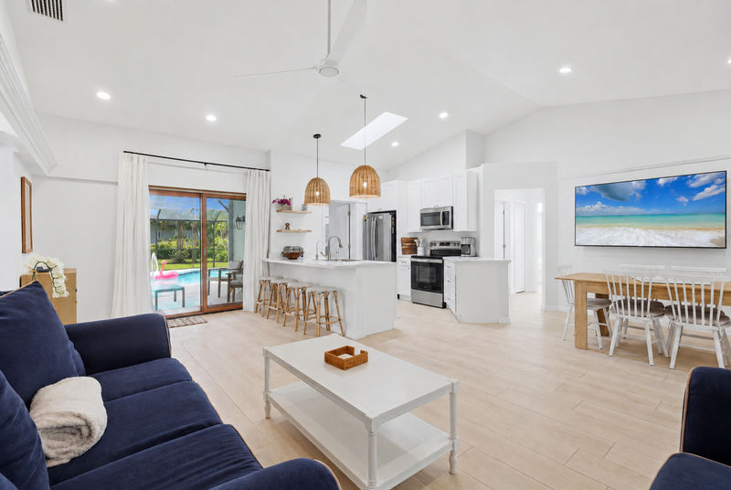 Bright, open living space with comfy seating, 75-inch Smart TV, and lanai access