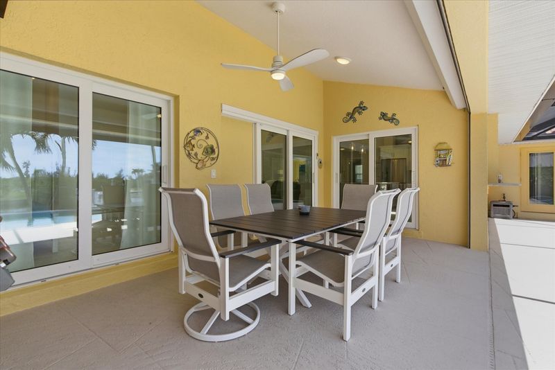 Large outdoor living space features a sparkling pool overlooking the canal, dining for 6, sun loungers, BBQ grill, and 50" Smart TV
