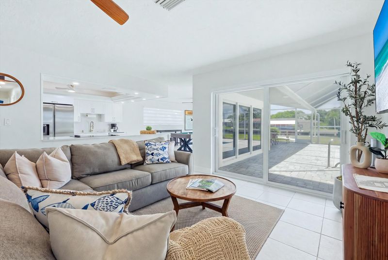 Living room overlooking pool & canal. Features lots of comfy seating and 75-inch Smart TV