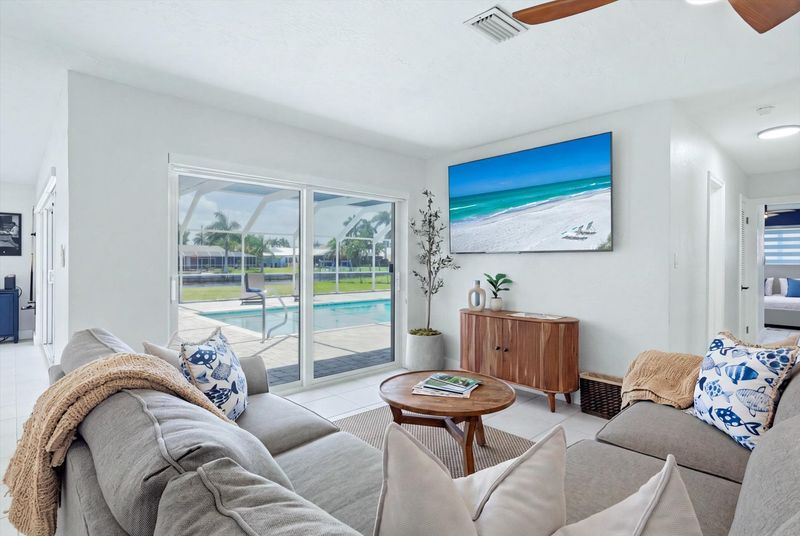 Living room overlooking pool & canal. Features lots of comfy seating and 75-inch Smart TV