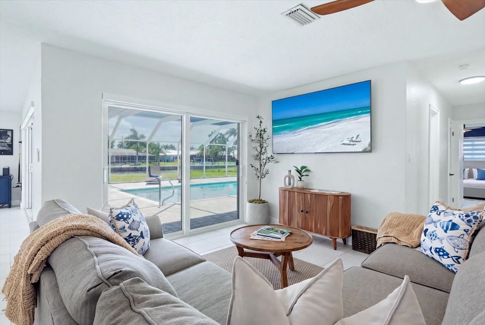 Living room overlooking pool & canal. Features lots of comfy seating and 75-inch Smart TV