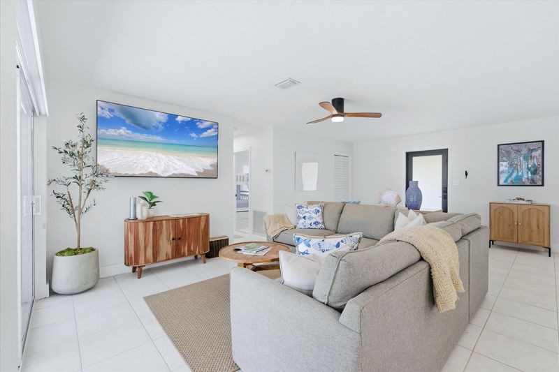 Living room overlooking pool & canal. Features lots of comfy seating and 75-inch Smart TV