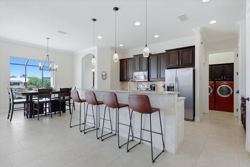Fully-equipped kitchen overlooking the living room and dining areas. The kitchen features lots of countertop & storage space, and stainless-steel appliances. Kitchen island seats 4