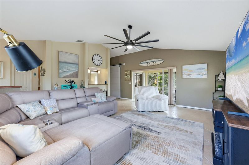 Living room features lots of comfy seating, patio access, and 85-inch Smart TV