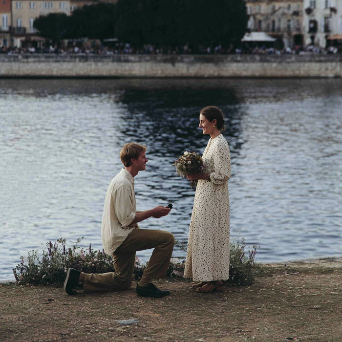 man proposing to a woman next to a city lake