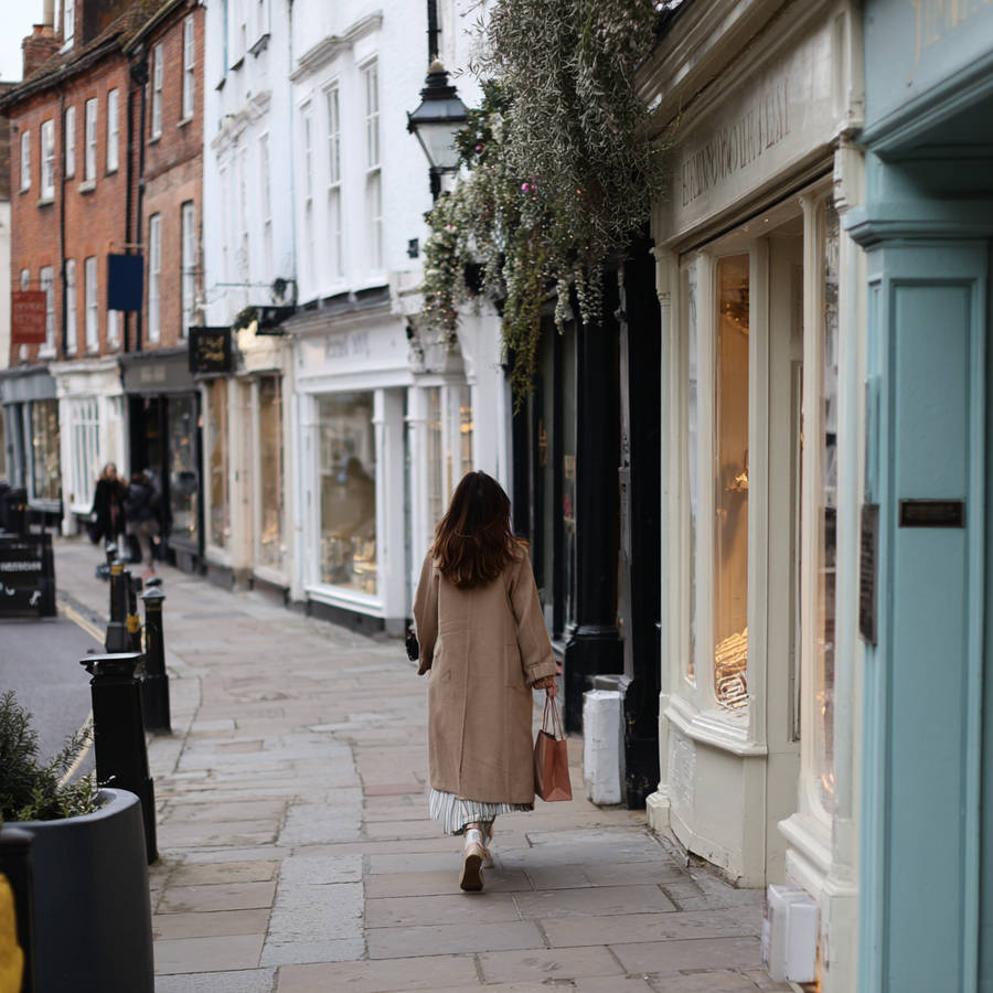 Woman walking along a charming high street lined with independent jewellery shops and boutique storefronts