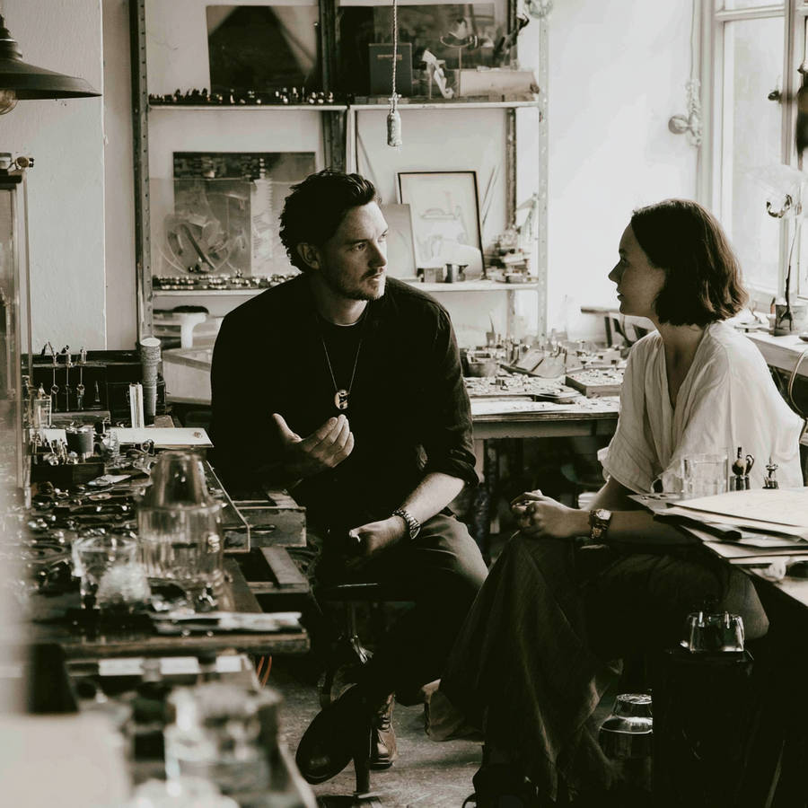 Jeweller consulting with a client in a workshop, discussing ideas for a bespoke engagement ring design.