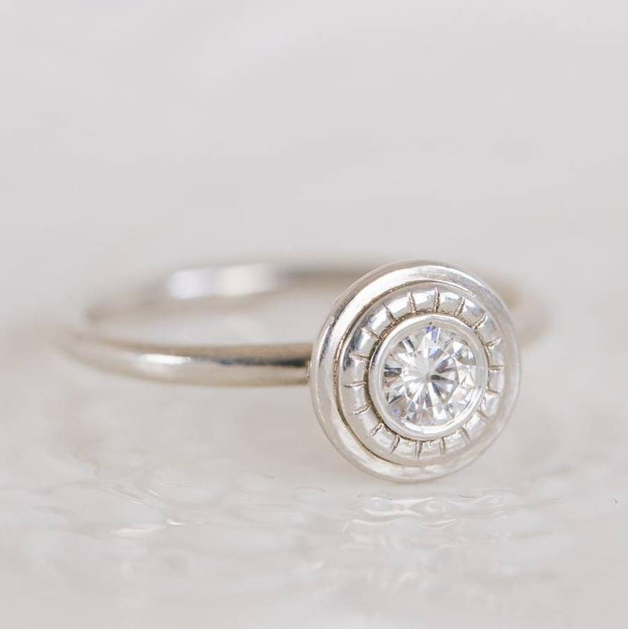 Bespoke bezel-set diamond engagement ring in polished white gold with delicate milgrain detailing on a clean white background