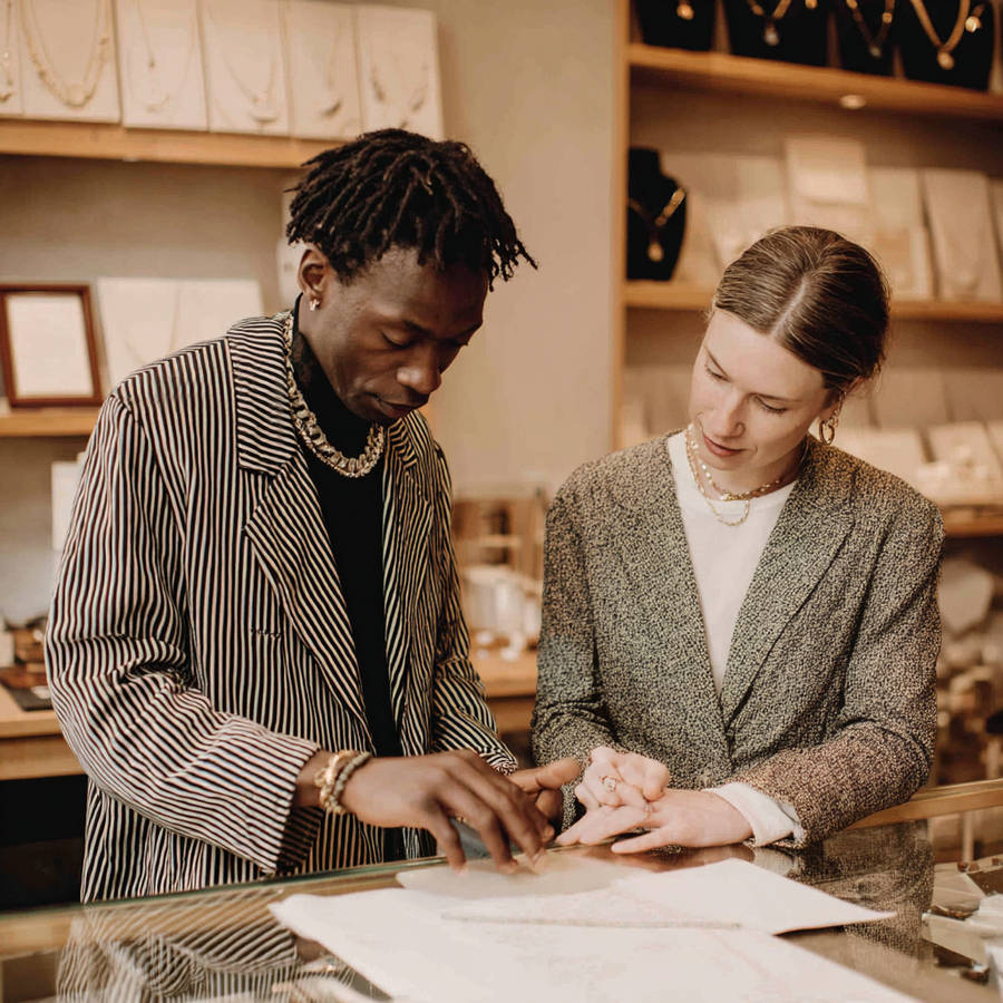Jeweller consulting with a client at a showroom counter, reviewing designs and jewellery pieces in a boutique.