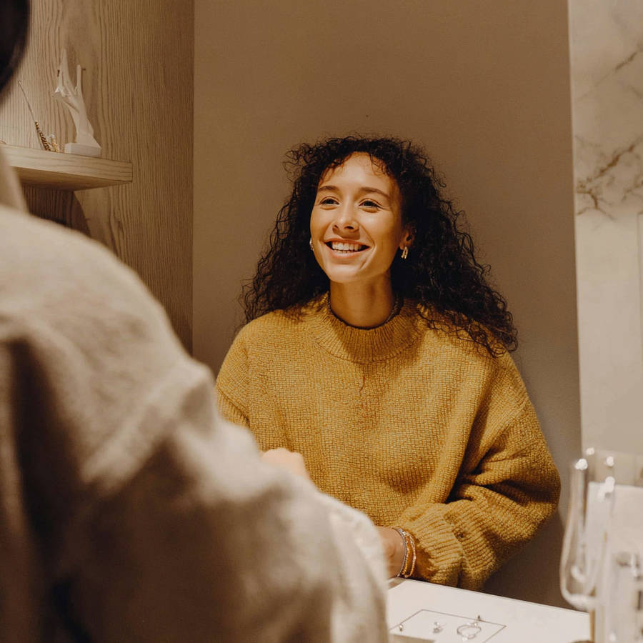 Woman smiling while speaking with a jeweller inside a boutique jewellery studio during a bespoke engagement ring consultation