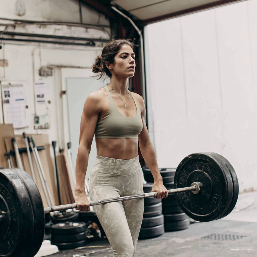 Fit woman lifting heavy barbell in industrial gym during strength training workout