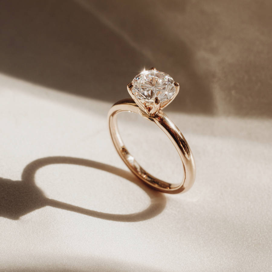 Profile view of a bespoke cathedral setting engagement ring with a round diamond and polished yellow gold band.