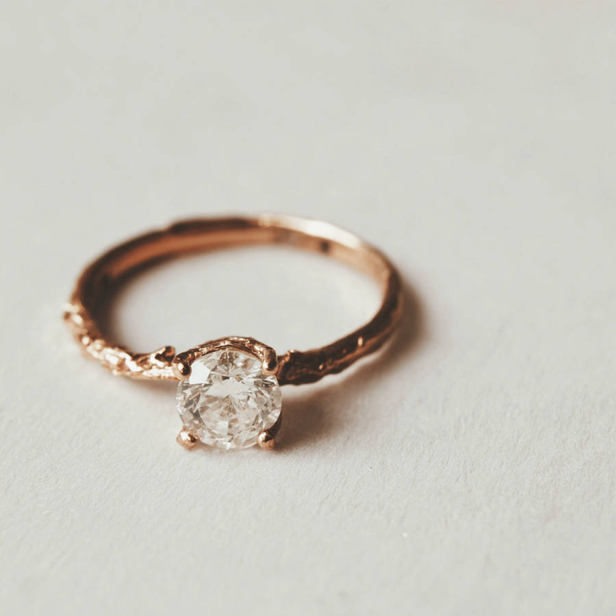 Bespoke rose gold solitaire engagement ring with round diamond on a soft white background.