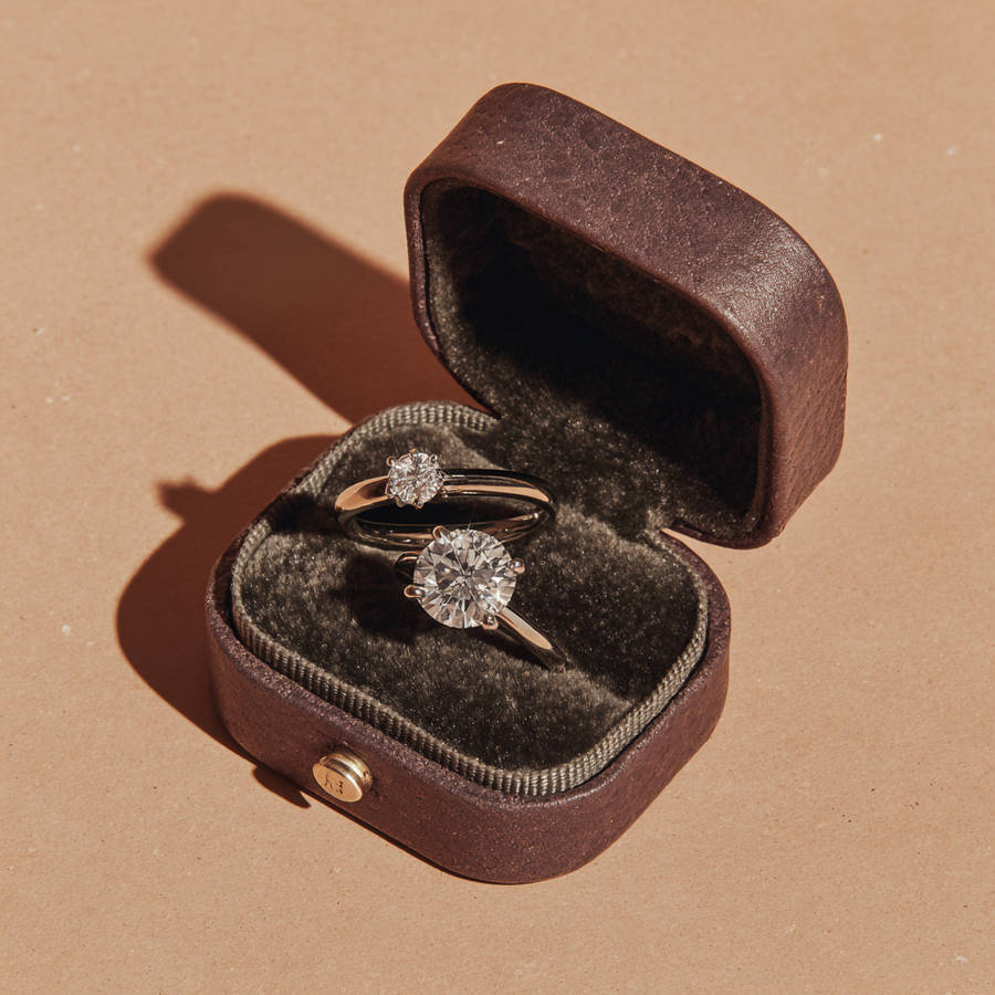 Custom diamond engagement ring and matching band displayed in an open velvet ring box with warm natural lighting