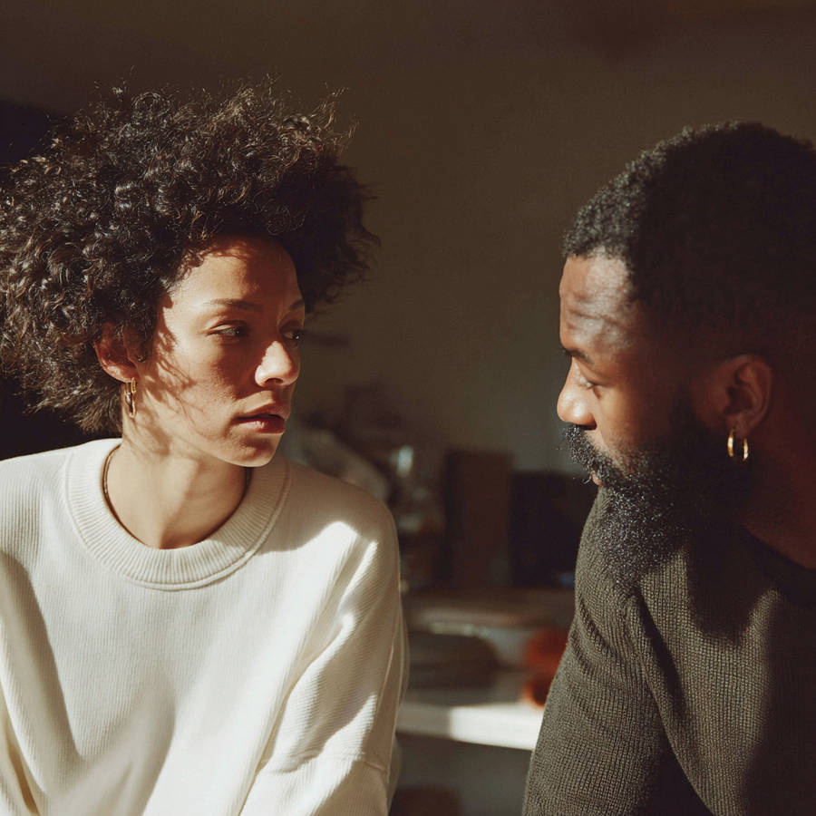Couple having an intimate conversation at home in warm natural light, capturing a thoughtful relationship moment