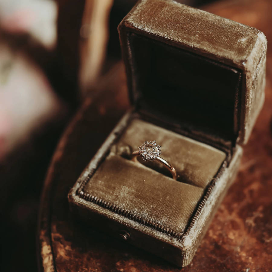 Custom diamond engagement ring in a vintage velvet ring box, photographed in warm light on a rustic surface