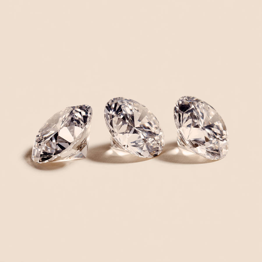 Three loose solitaire diamonds displayed in a row on a neutral background for bespoke engagement ring design inspiration