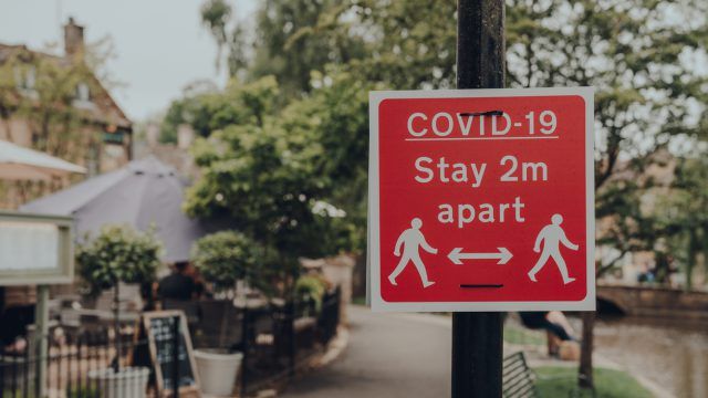 Sign reading "Covid-19: stay 2m apart" - One year on from