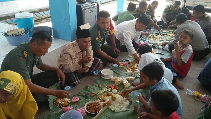 Satgas TMMD Kodim 0824/Jember, menikmati hidangan makan siang bersama kaum Dhuafa. (FOTO: NUSANTARANEWS.CO/Singgih)