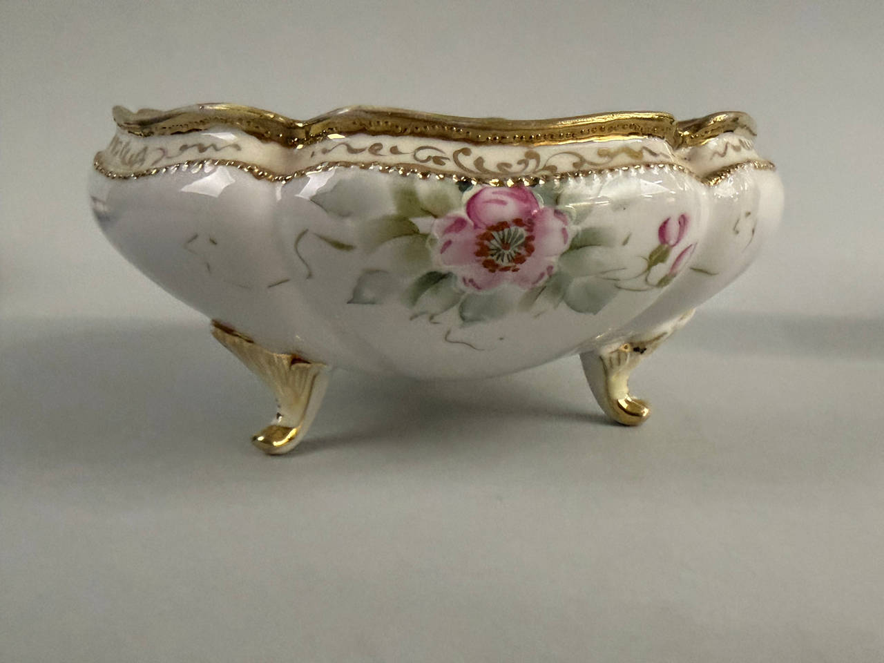 A hand-painted Nippon porcelain footed bowl with floral motifs and gold trim.