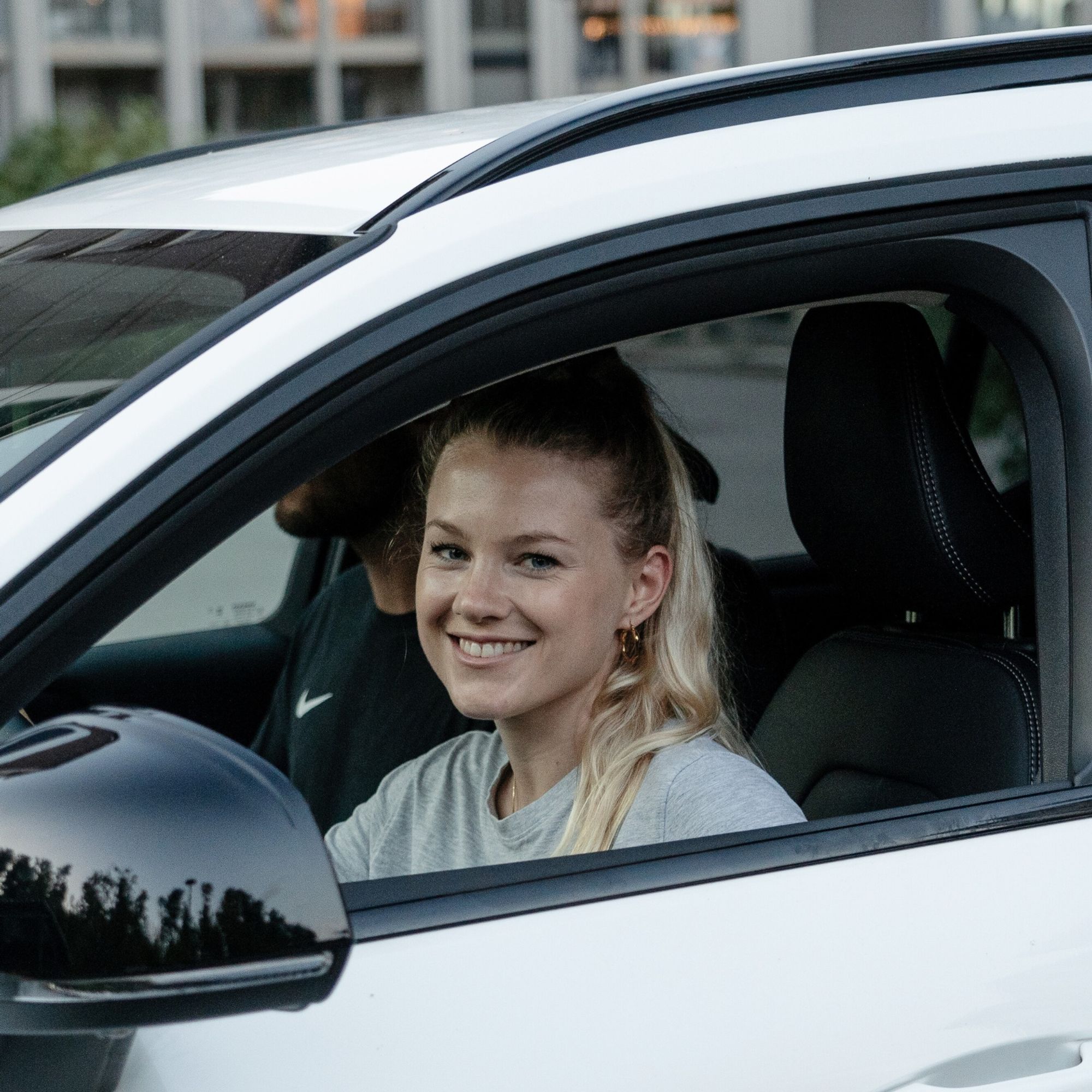 Junge Frau sitzt im Auto und schaut in die Kamera