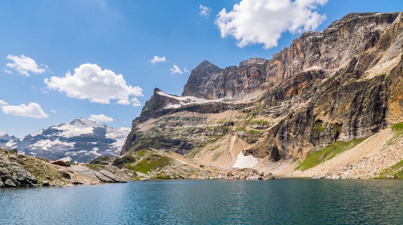 Lac de la Roche Ferran is a small but worthwhile detour from the Tour de la Vanoise trail. The lake is fed by the glacier above it, and the view opens toward the Dôme de Chasseforêt rising above the Vanoise Glacier.