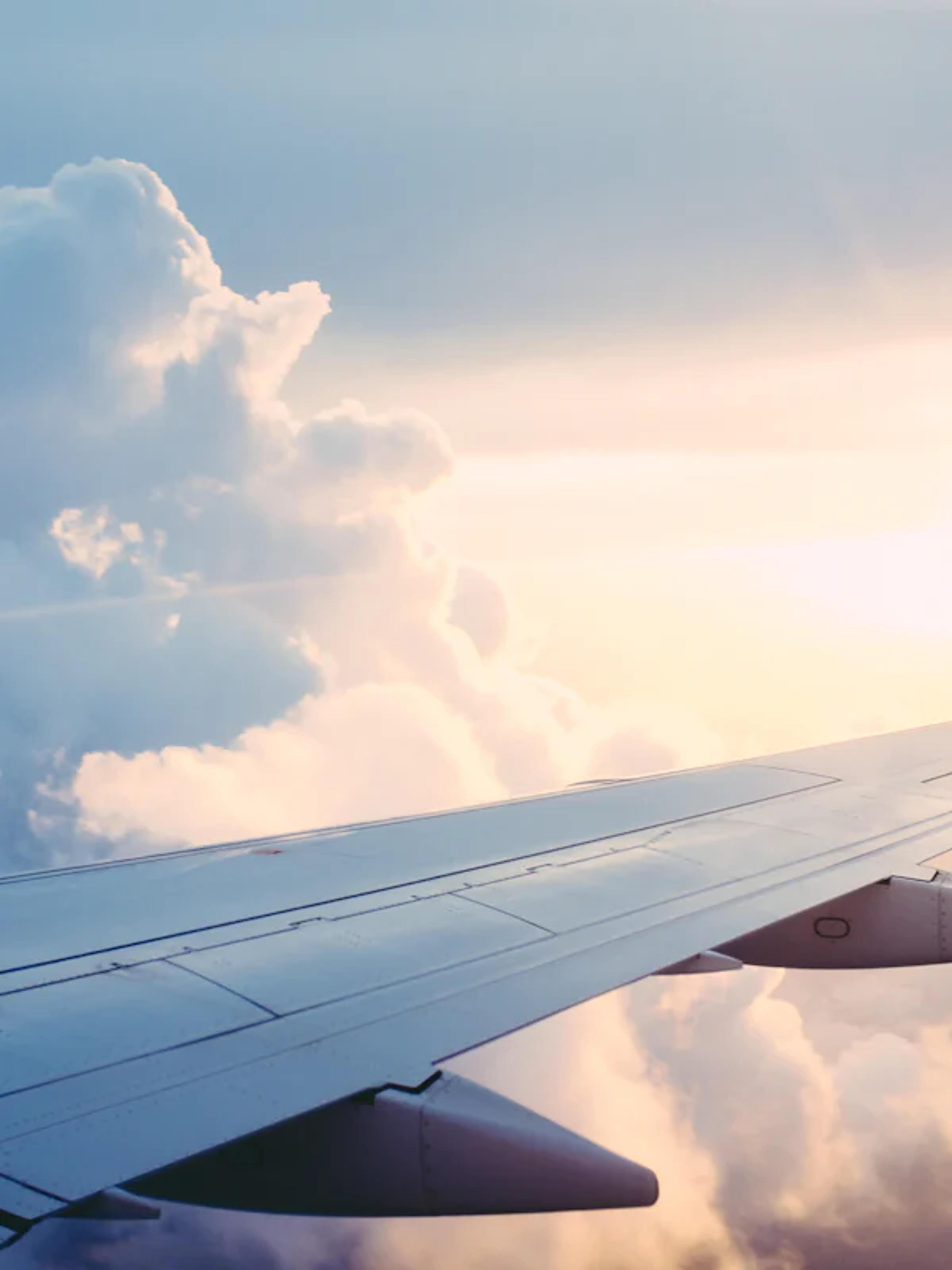 Airplane wing above the clouds at sunset