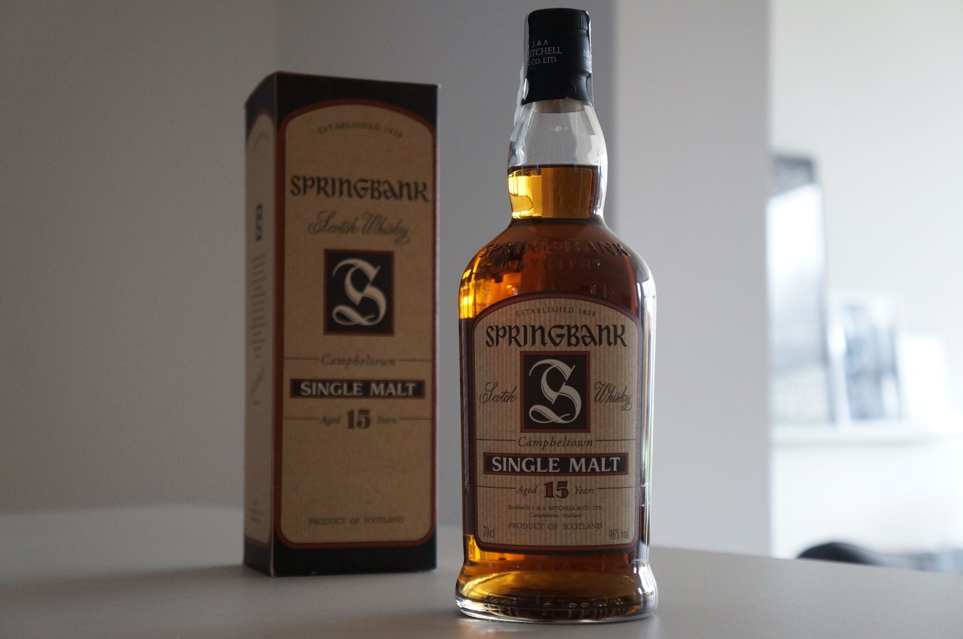 一瓶 Springbank 15年威士忌，背景是溫暖的燈光和橡木桶