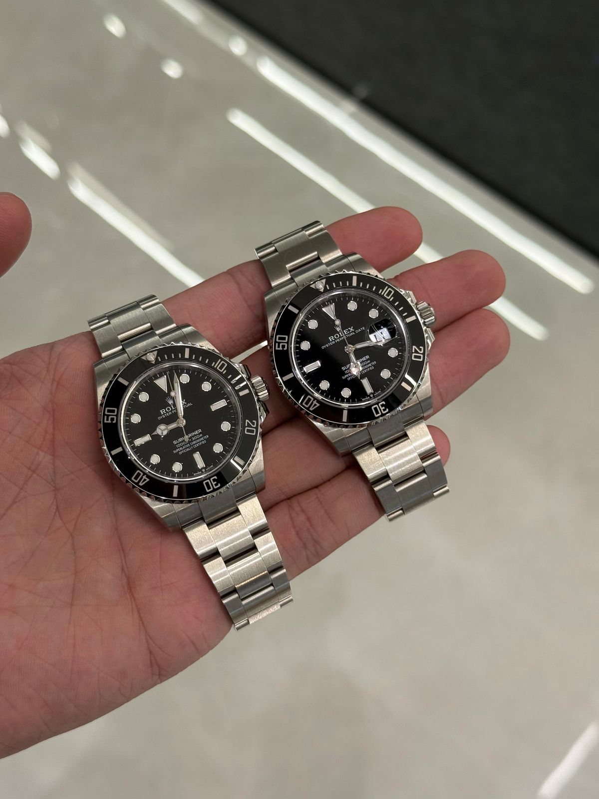 手掌托着兩隻黑面腕錶，可見金屬三格鍊帶和錶頭接駁位置