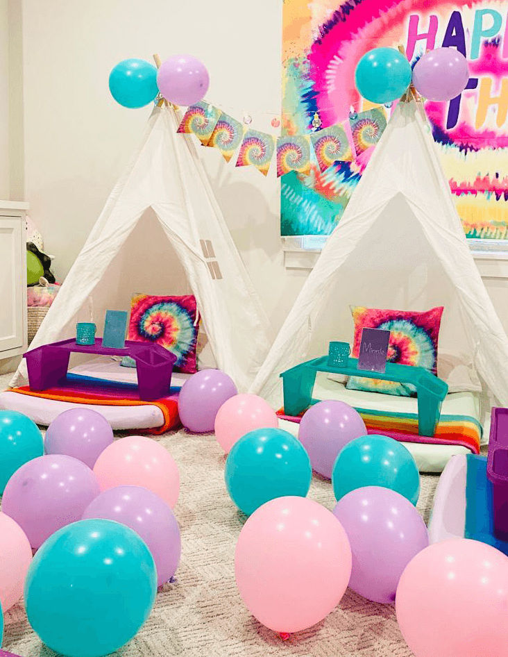 Slumber party and teepee party with a group of balloons on a bed