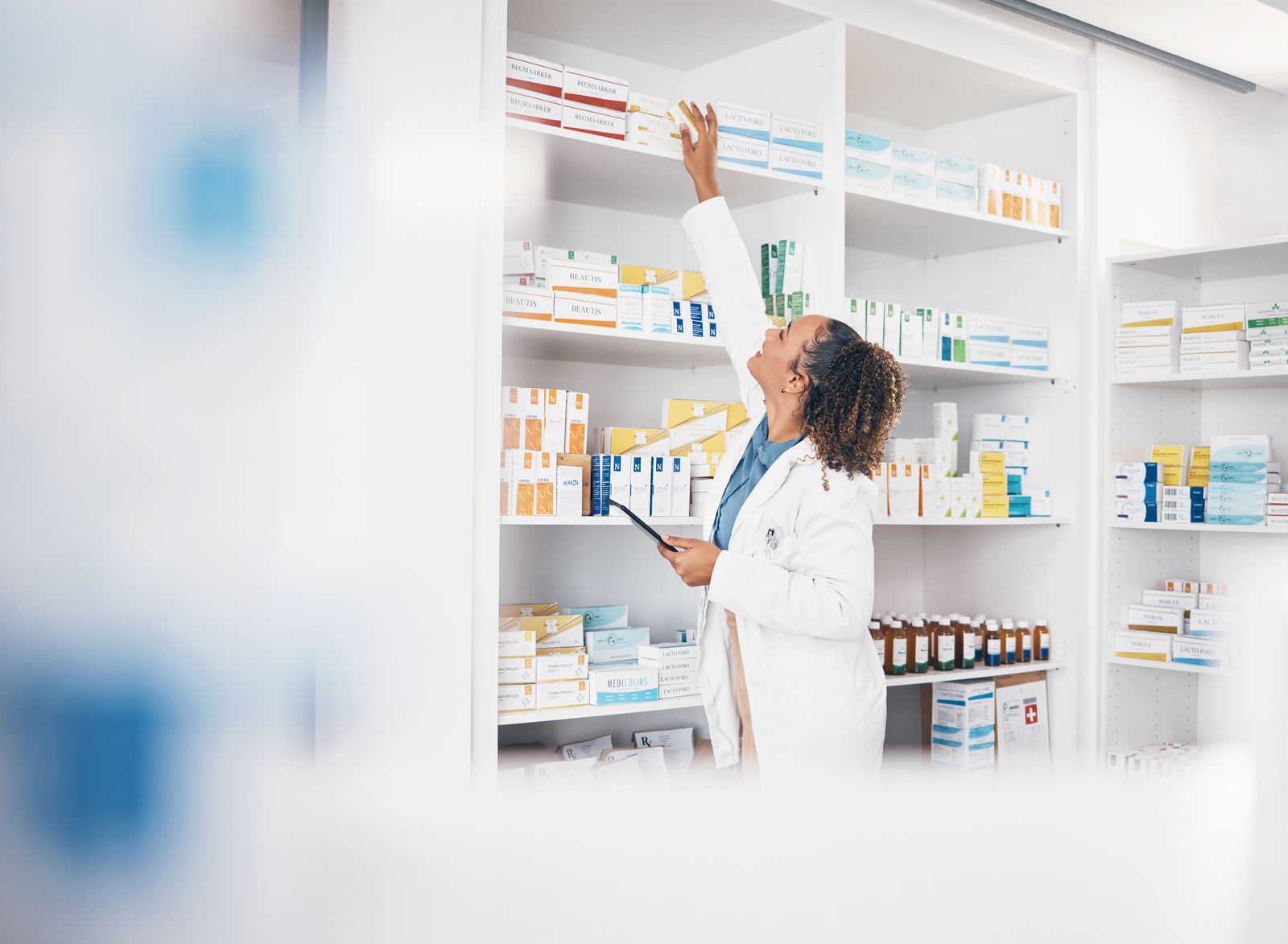 Pharmacist reaching for shelf medication